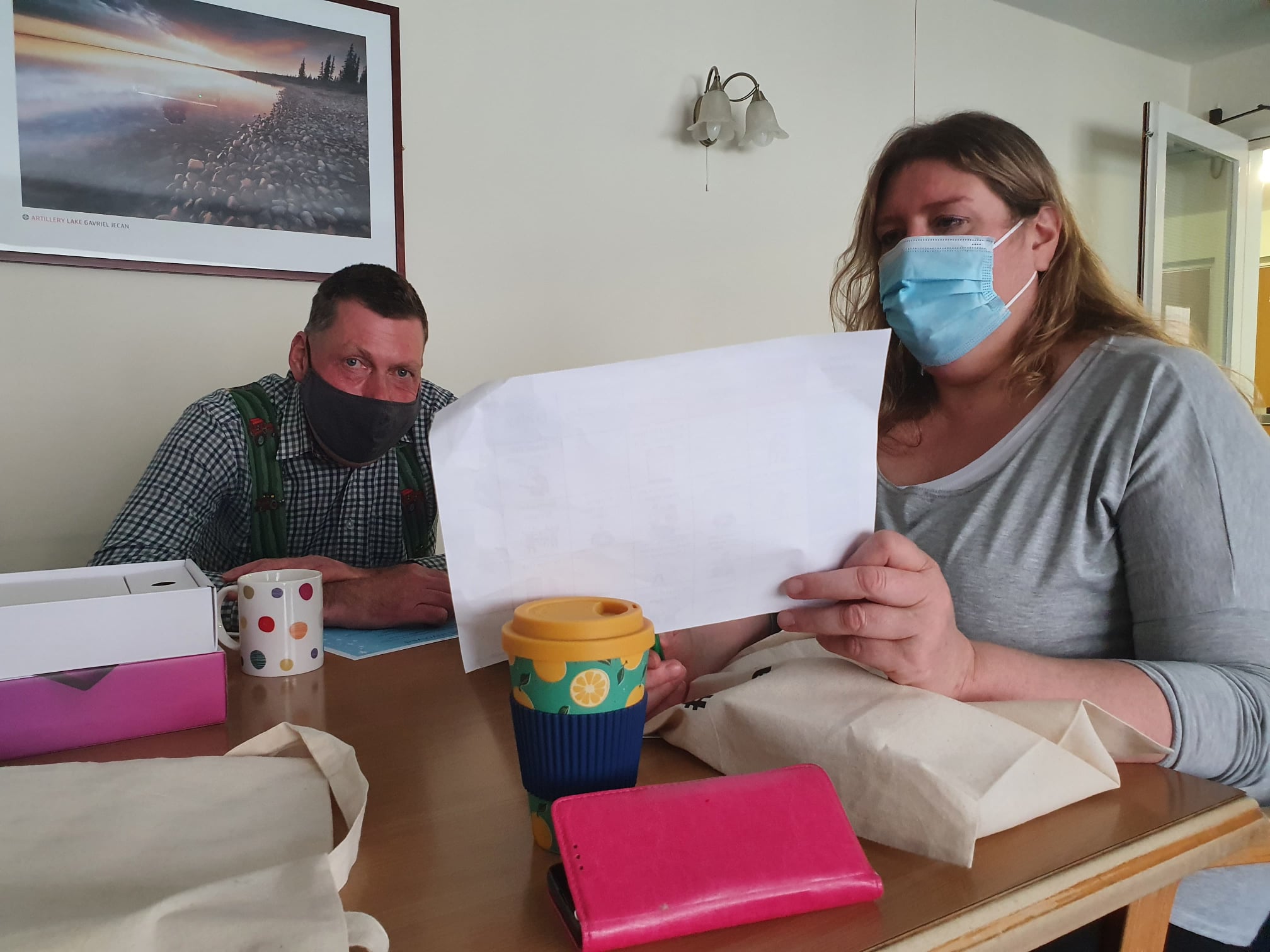 two people talking at a table holding a paper